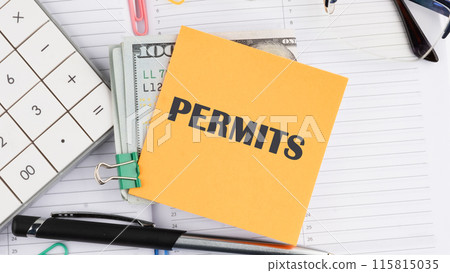 Business concept, Permit word written on a yellow sticker next to American hundred dollar bills, a calculator, a pen on a white background 115815035