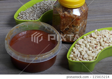 Honey in a container. Next to separate containers of peanuts and sunflower seeds. Ingredients for making halva. 115815214