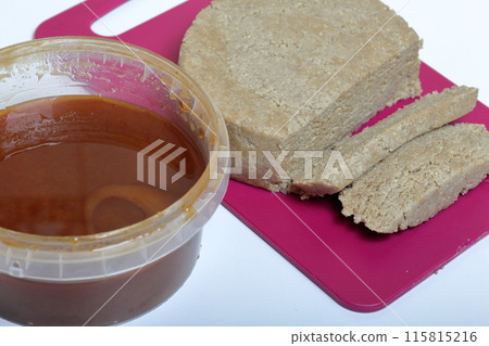 Sliced halva from honey, peanuts and sunflower seeds. Next honey in the container. Ingredients and tools for making halva. Sliced halva from honey, peanuts and sunflower seeds. Next honey in the container. Ingredients and tools for making halva. 115815216