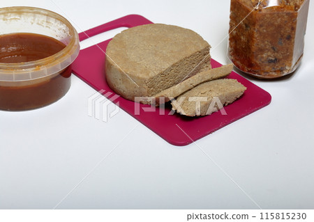 Sliced halva from honey, peanuts and sunflower seeds. Near honey in different containers. Ingredients and tools for making halva. 115815230