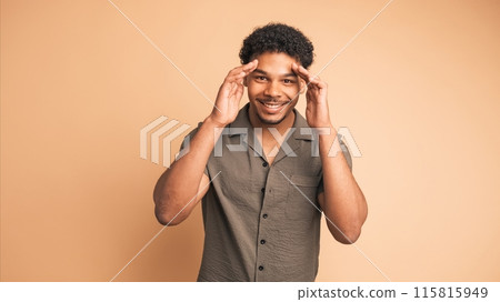 Surprise young man smiling at camera in beige studio Surprise young man smiling at camera in beige studio 115815949