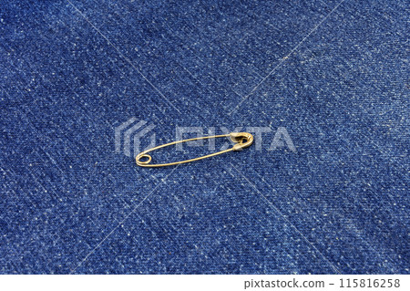 In blue jeans material is a metal pin fastened 115816258