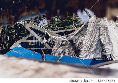 Old and rusty motor boats on a landfill surrounded by tropical forest 115816875