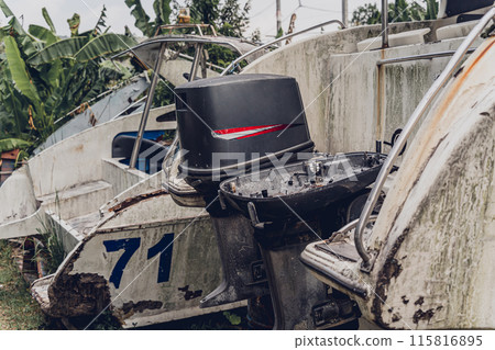 Old and rusty motor boats on a landfill surrounded by tropical forest 115816895
