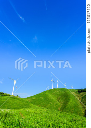A view of wind power plants towering over the vast outdoors against the backdrop of a blue sky (Aso Nishihara Wind Farm) 115817320