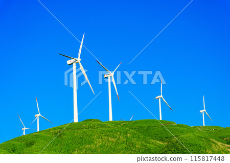 A view of wind power plants towering over the vast outdoors against the backdrop of a blue sky (Aso Nishihara Wind Farm) 115817448