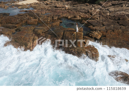 Woman on Rocky Shoreline with Crashing Waves Woman on Rocky Shoreline with Crashing Waves 115818639