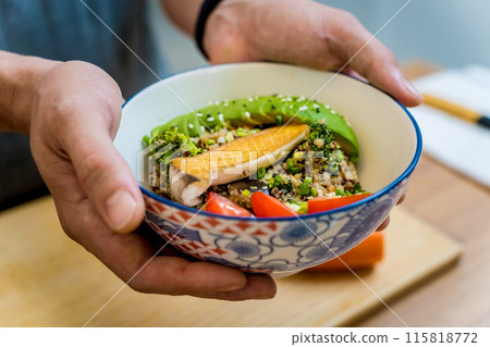 Chef at the kitchen preparing healthy quinoa bowl with avocado 115818772
