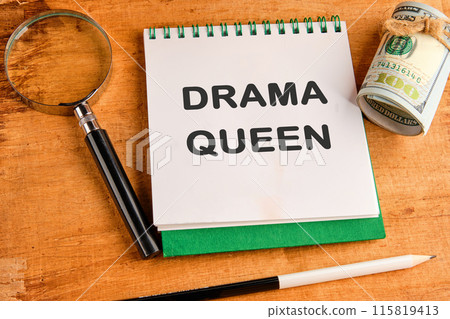 Text DRAMA QUEEN in a notebook in a composition with a magnifying glass, dollars and a pencil Text DRAMA QUEEN in a notebook in a composition with a magnifying glass, dollars and a pencil 115819413