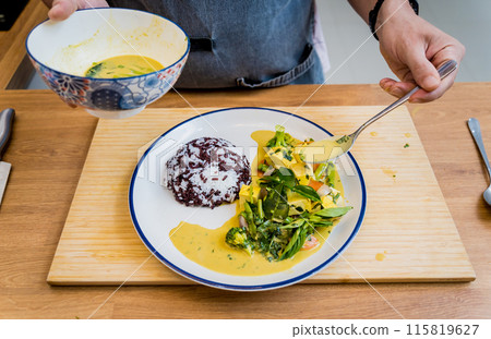 Chef at the kitchen preparing green curry with herbs and rice Chef at the kitchen preparing green curry with herbs and rice 115819627