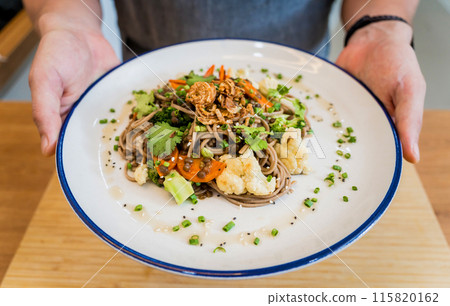 Chef at the kitchen preparing japanese buckwheat pasta with lentils 115820162