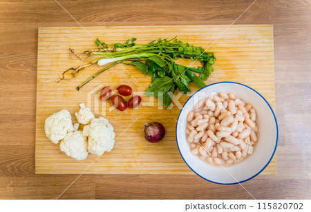 Cutting board with ingredients for preparing bean porridge with cauliflower and vegetables 115820702