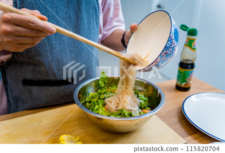 Chef at the kitchen preparing spicy glass noodle salad 115820704