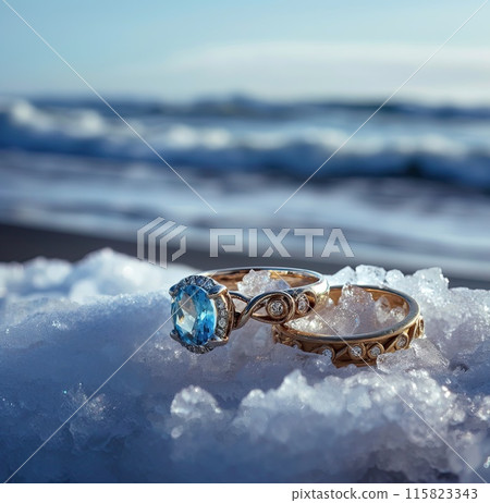 Elegant aquamarine engagement ring paired with a detailed band, showcased on a piece of ice against a blurry ocean backdrop.. Elegant aquamarine engagement ring paired with a detailed band, showcased on a piece of ice against a blurry ocean backdrop.. 115823343