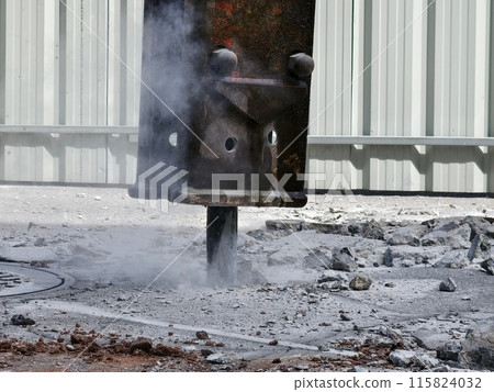 A hydraulic hammer breaking concrete at a construction site 115824032