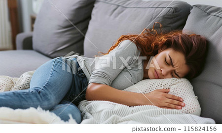 Woman with period or abdominal pain on a sofa Woman with period or abdominal pain on a sofa 115824156