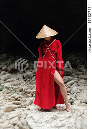 Asian girl in a beautiful red kimono and a Vietnamese triangular hat poses sexually in the bosom of nature in a rocky canyon Asian girl in a beautiful red kimono and a Vietnamese triangular hat poses sexually in the bosom of nature in a rocky canyon 115827314