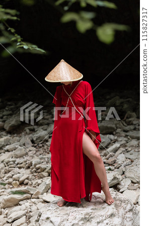 Asian girl in a beautiful red kimono and a Vietnamese triangular hat poses sexually in the bosom of nature in a rocky canyon Asian girl in a beautiful red kimono and a Vietnamese triangular hat poses sexually in the bosom of nature in a rocky canyon 115827317