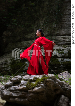 Asian girl in a beautiful red kimono in the middle of nature in a canyon Asian girl in a beautiful red kimono in the middle of nature in a canyon 115827325