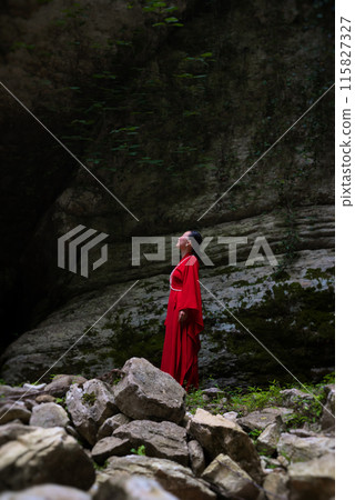 Asian girl in a beautiful red kimono in the middle of nature in a canyon Asian girl in a beautiful red kimono in the middle of nature in a canyon 115827327