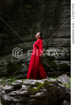 Asian girl in a beautiful red kimono in the middle of nature in a canyon Asian girl in a beautiful red kimono in the middle of nature in a canyon 115827343