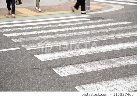 The feet of a person waiting for the traffic light at a pedestrian crossing 115827463