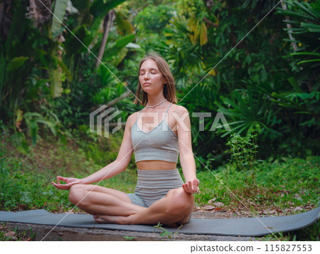 Beautiful woman practices yoga by pool in morning in Crabi, Thailand. portrait of joyful female sitting in Lotus pose keeping mental and physical strength during yoga concentration at jungle 115827553