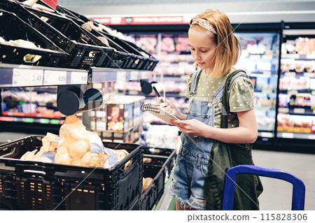 Pretty girl child buying vegetables with shopping list in supermarket and checking products with notes. Beautiful female preteen kid in grocery store 115828306
