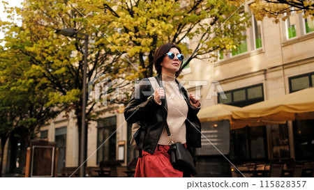 Attractive Woman In Sunglasses Walks In City With Backpack, Female Tourist Looking Around 115828357