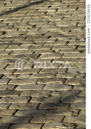 Stone paving stones in the evening sun with shadows. Stone paving stones in the evening sun with shadows. 115829416