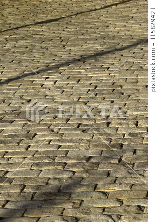 Stone paving stones in the evening sun with shadows. 115829421