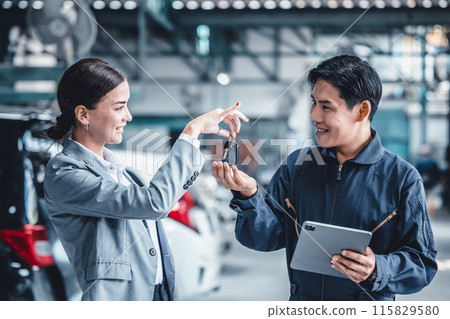 Business women happy customer giving a car key for vehicle maintenance to garage service team. 115829580