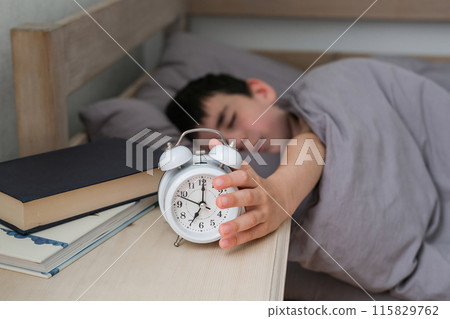 Sleepy boy reaches for the alarm clock. Morning of the schoolboy 115829762