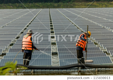 Worker Cleaning floating solar panels or solar cell Platform system on the lake with brush and water 115830013