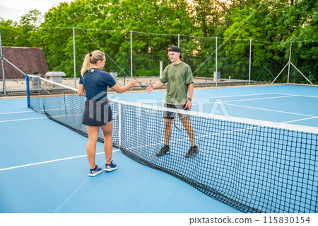 Professional tennis players shaking hands at the end of a tennis game on outside court Professional tennis players shaking hands at the end of a tennis game on outside court 115830154