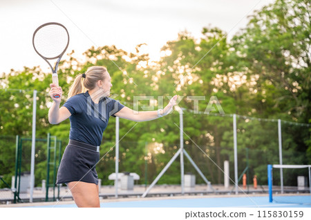 Professional female tennis player playing in tennis with racket and ball on outside court at sunset light 115830159