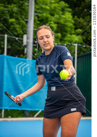 Professional female tennis player serving the tennis ball during playing on outside court 115830164