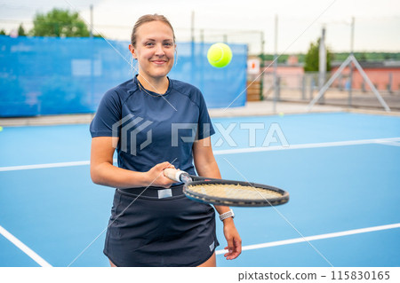 Professional female tennis player posing with the tennis racket and ball on outside court 115830165