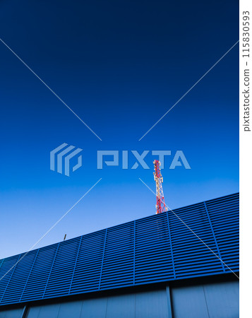 A TV tower on the background of a clear, evening, blue sky, and a building 115830593