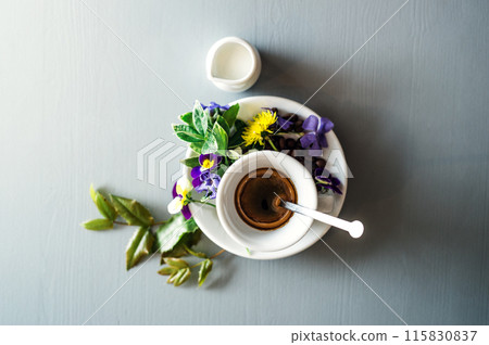 Cup with hot espresso, with pansy flower on top. 115830837