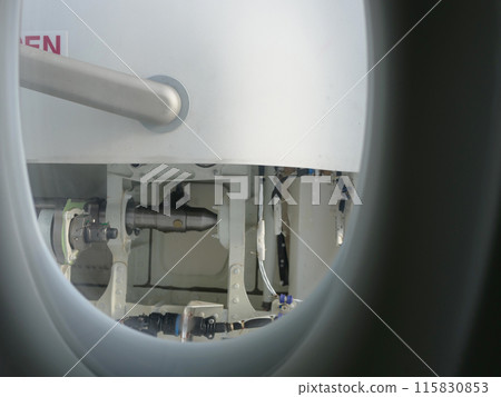 Through aircraft window on passenger seat details of door visible. Perfect for travel and aviation content. Window view showing aircraft interior and door perspective through window during flight. 115830853