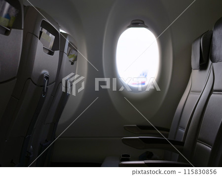 window in plane is from inside empty chairs are visible for travel and aviation content view of illuminator showing and comfort of cabin, tranquility and spaciousness through scenes with illuminator. 115830856