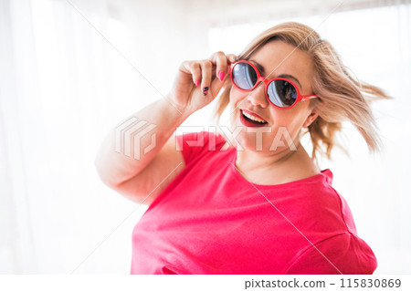 Portrait of beautiful young overweight woman at home, with sunglasses. Portrait of beautiful young overweight woman at home, with sunglasses. 115830869