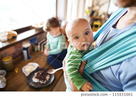 Father holding small baby, carrying him around house in baby carrier. Unconditional paternal love, father's Day. 115831001