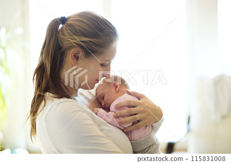 Mom holding newborn baby, looking at infant lovingly. Unconditional paternal love, Mother's Day concept. 115831008