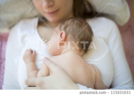 New mom lying on bed by newborn baby girl. Unconditional paternal love, idyllic family moment. 115831031