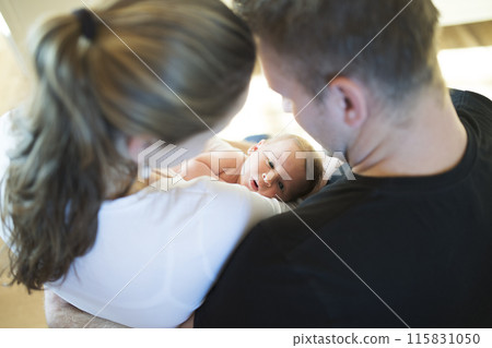 New parents holding newborn baby girl. Unconditional paternal love, idyllic family moment. New parents holding newborn baby girl. Unconditional paternal love, idyllic family moment. 115831050