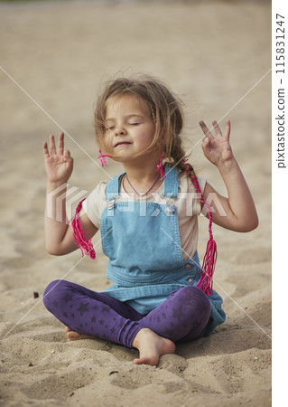 child doing yoga on the beach in Denmark 115831247