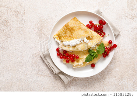 Crepes or thin pancakes with cheese cottage or curd and fresh red currant berries, top view Crepes or thin pancakes with cheese cottage or curd and fresh red currant berries, top view 115831293