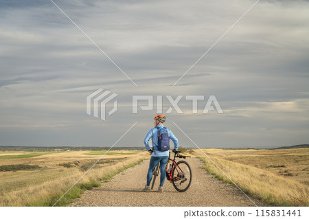 male cyclist with a gravel bike on a ranch road in Colorado foothills in spring scenery 115831441